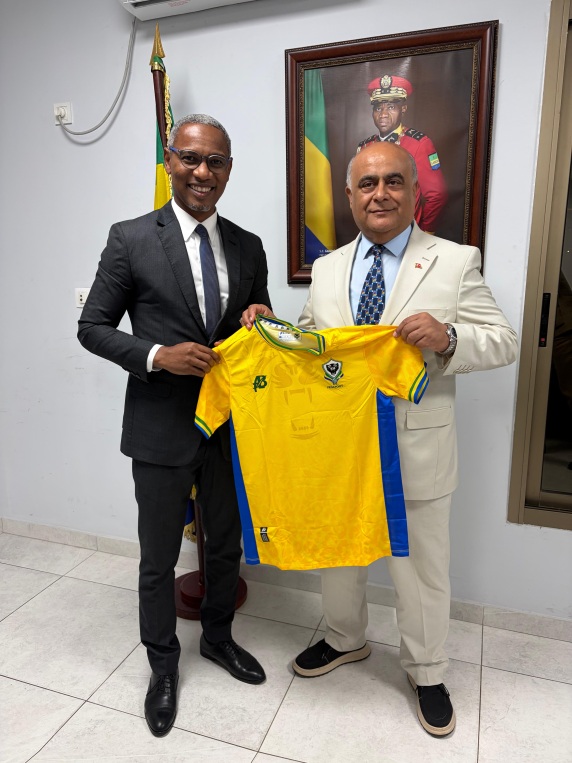 Two men holding a shirt, according to the caption Gabon’s sports minister and Numan Hatipoglu.